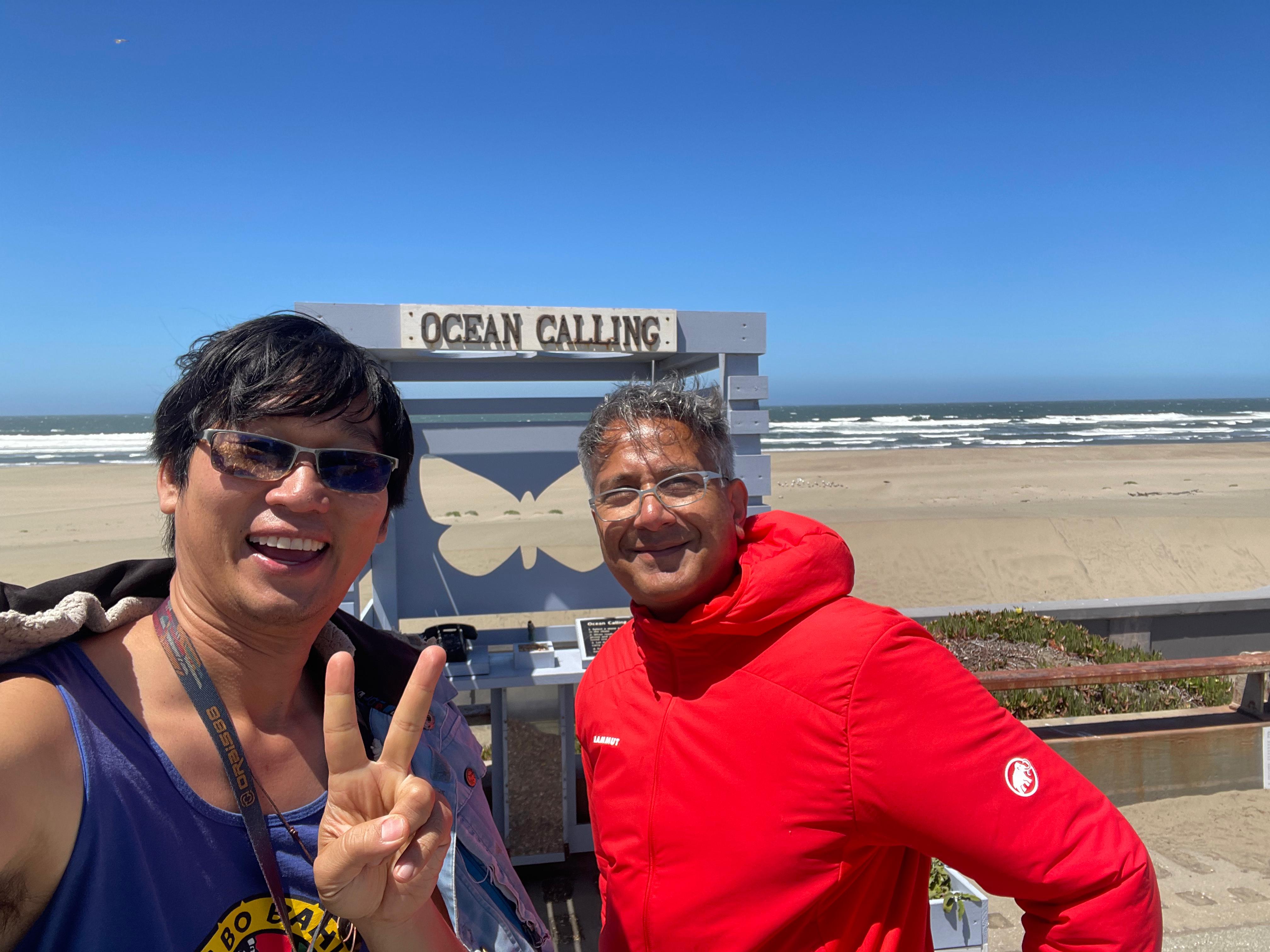 Gary and Bilal walking at Ocean Beach in San Francisco, with the Pacific behind them